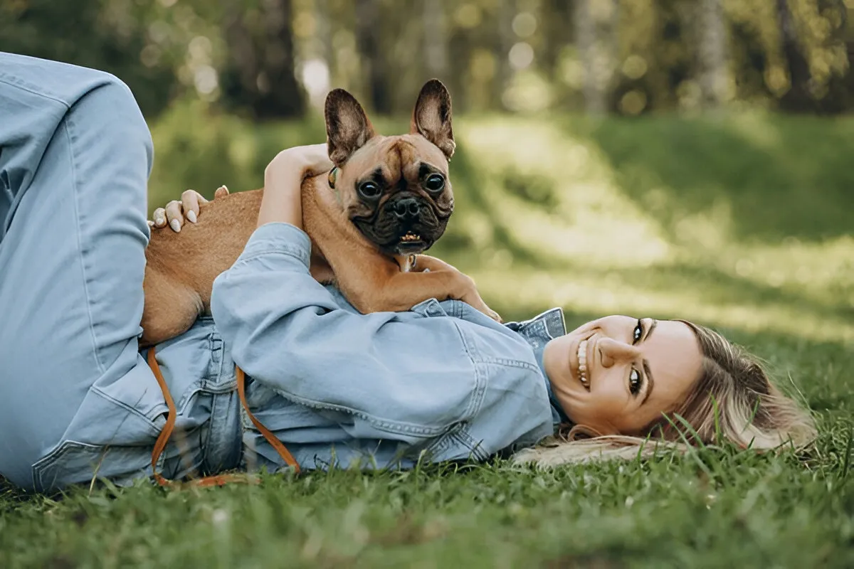 Smiling woman lying on grass with her puppy after a first puppy training session in Chicago, highlighting bonding and trust-building outdoors.
